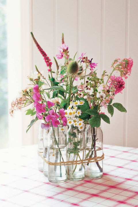 Arreglo floral con botellas de leche antiguas.